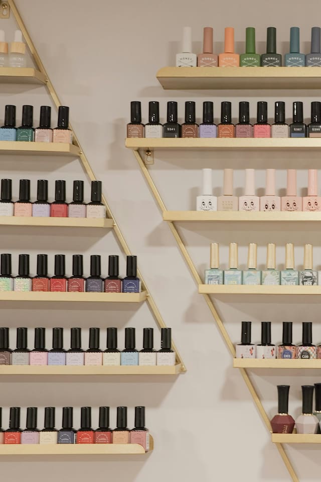Wall of gel and regular polish colors on gold shelves
